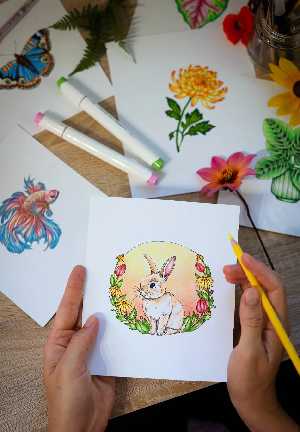 Rachel's hands coloring a bunny illustration with a yellow pencil